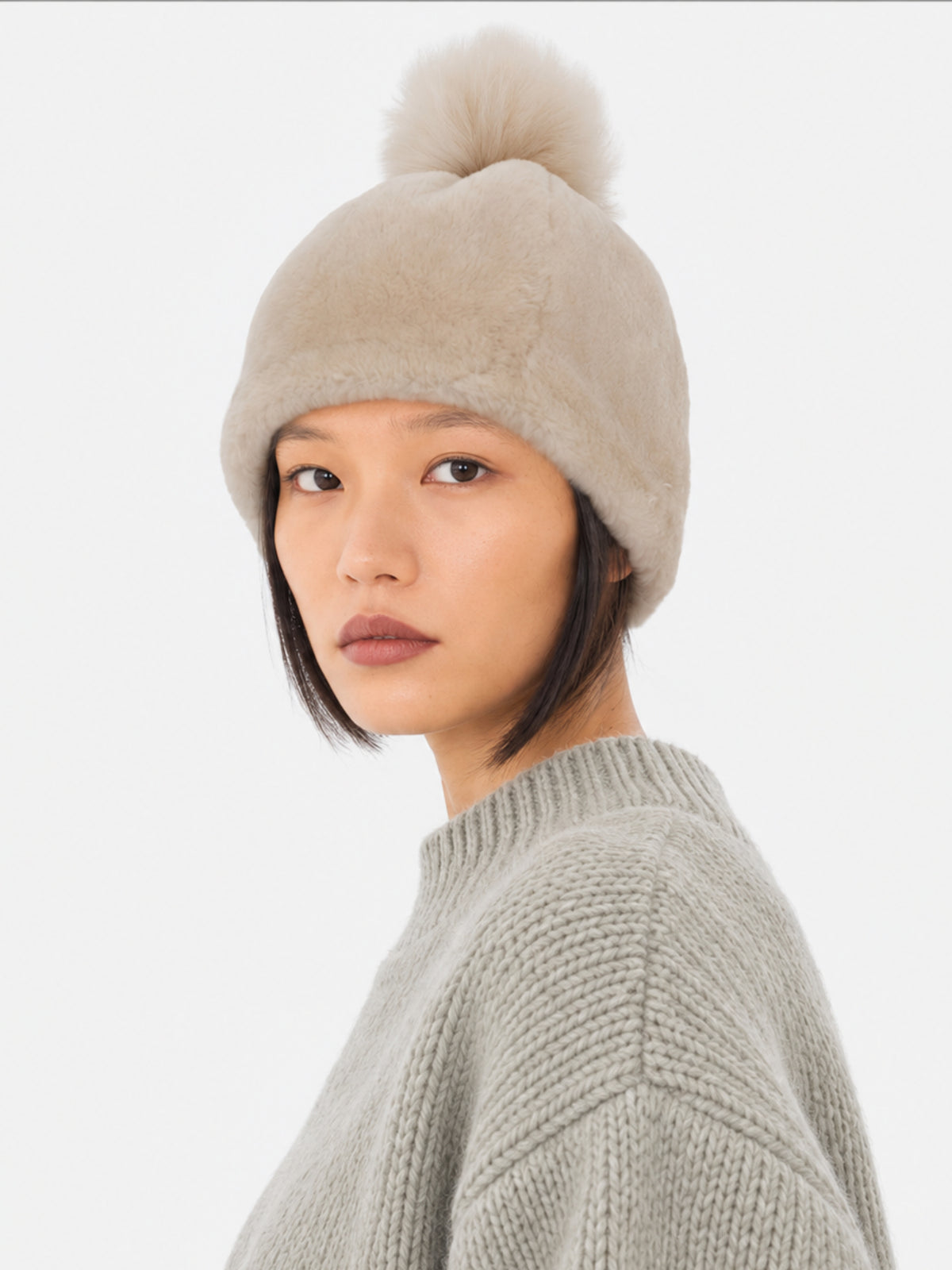 Model wearing the beige Toscana pompom hat by Dom Goor with a grey knit jumper, front view