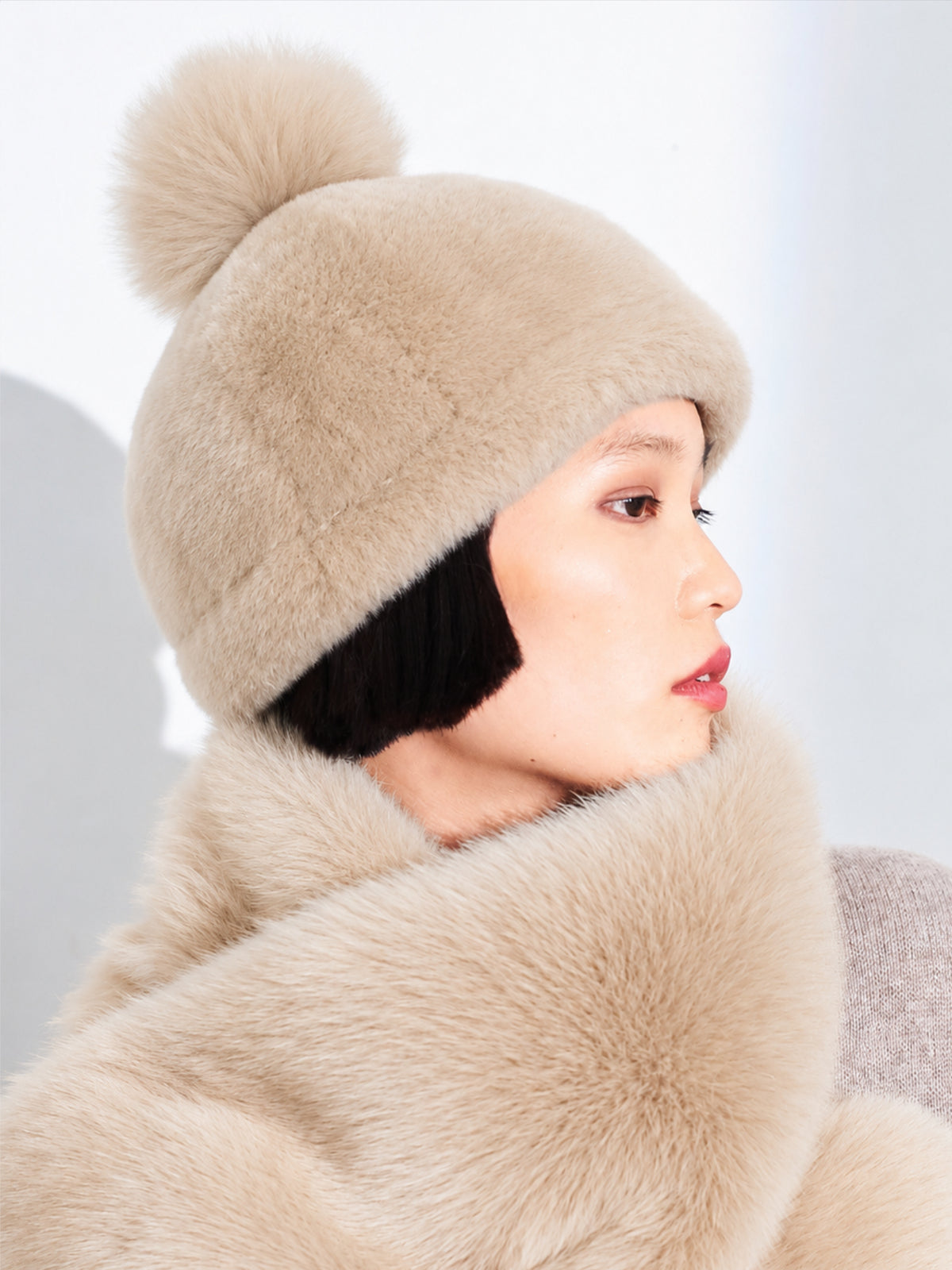 Beige Toscana pompom hat by Dom Goor on a model, side profile with a shearling scarf