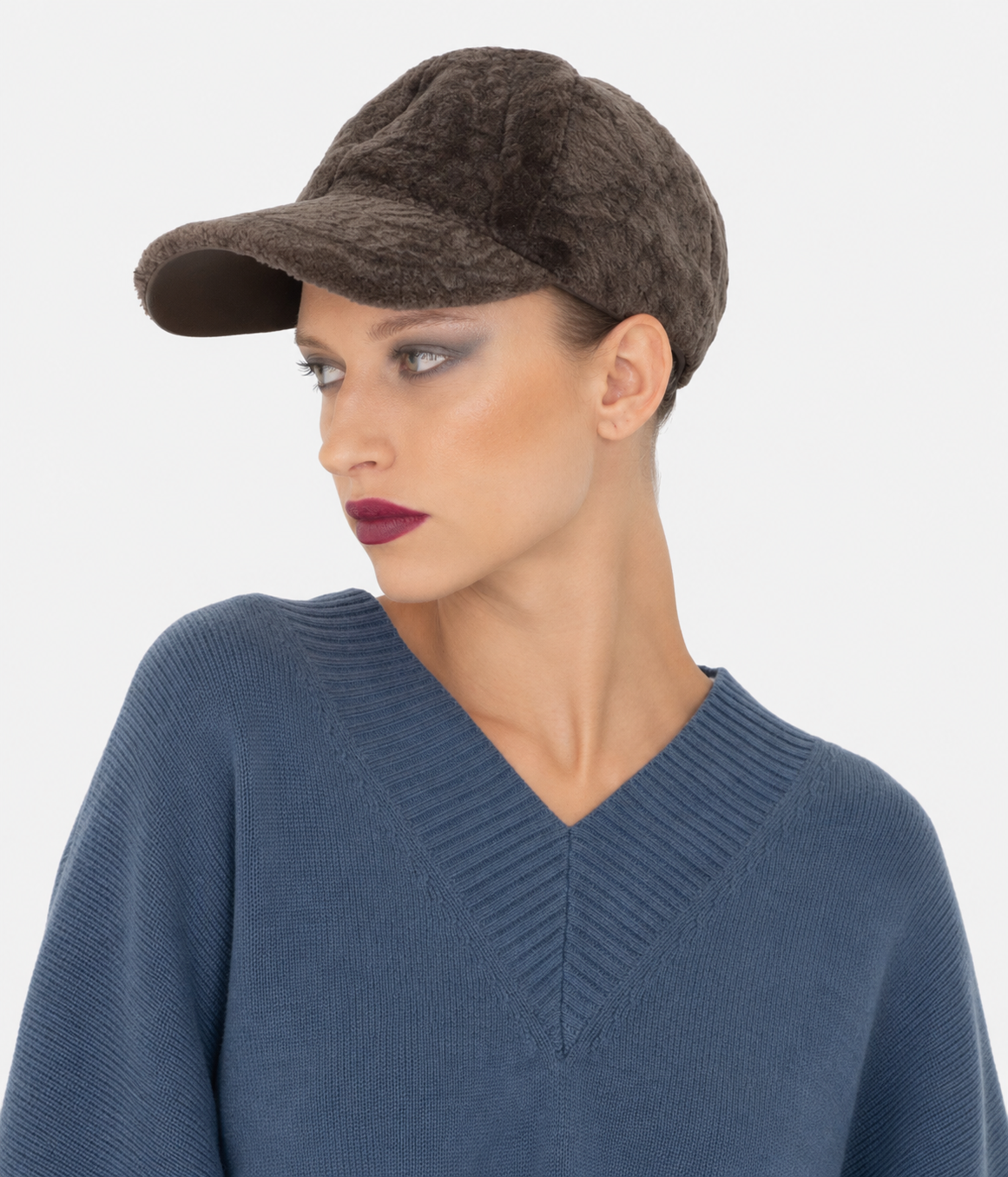 Brown astrakhan-pattern shearling baseball cap by Dom Goor on a model, side angle showing the peak