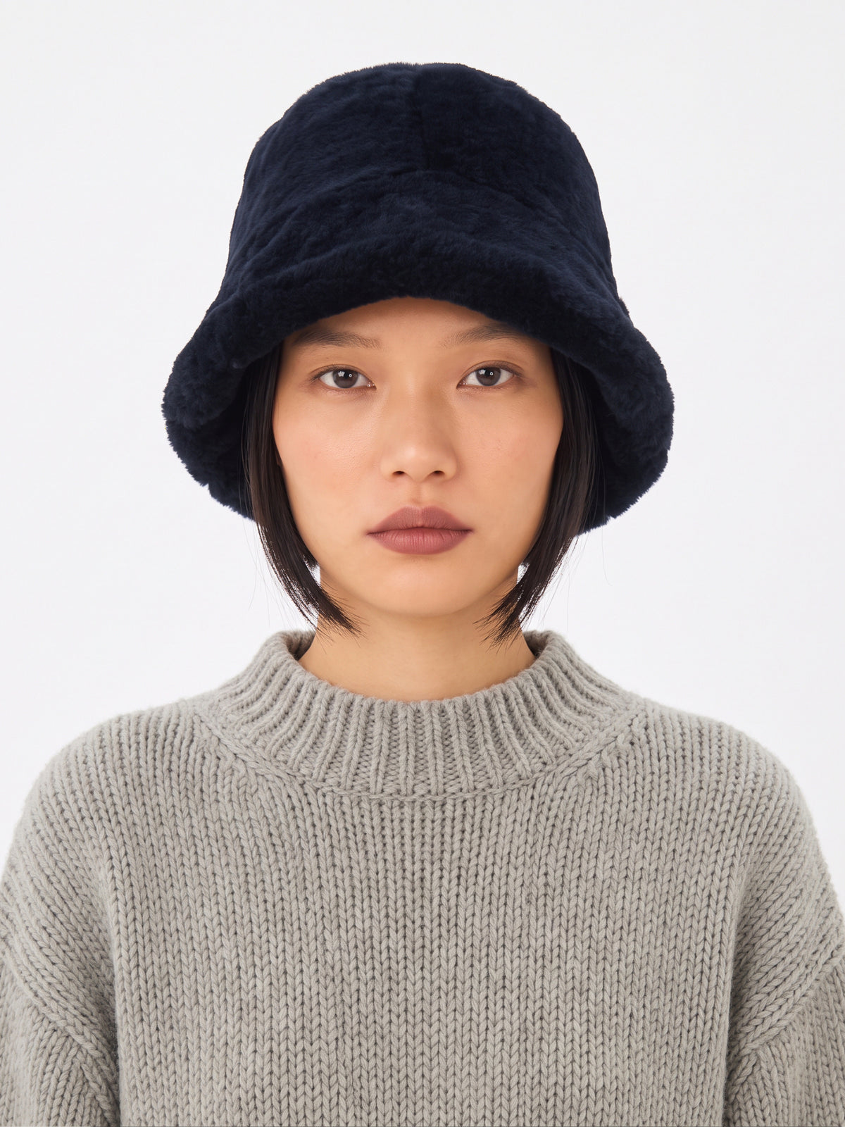 Model wearing the Dom Goor navy shearling bucket hat with a grey knit jumper, front view